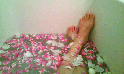 花びらを入れて半身浴をする女性の足の画像